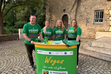 Vier Personen stehen hinter einem Aufsteller und machen Werbung für die WOGES