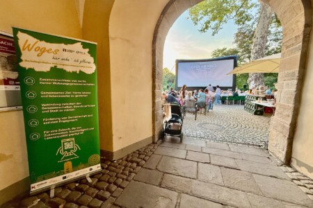 Blick durch den Eingang. Links steht ein Werbebanner der WOGES. Im Hintergrund erkennt man die Kinoleinwand