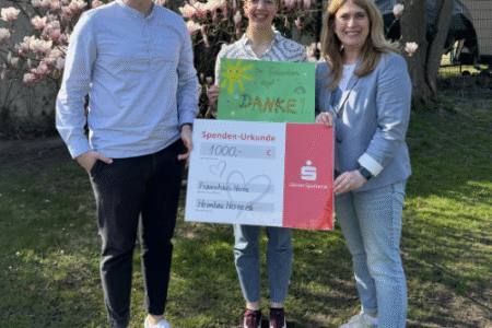 Drei Personen halten einen Spendencheck in der Hand. Die mittlere Person dazu noch ein Plakat auf dem gemalt wurde.