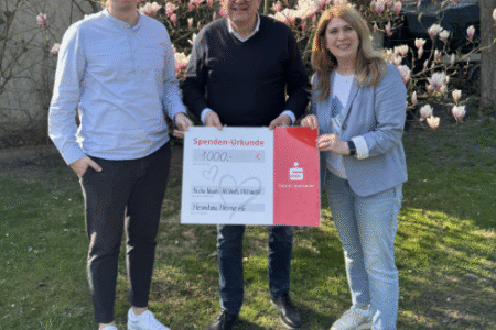 Drei Personen halten einen Spendencheck in der Hand.