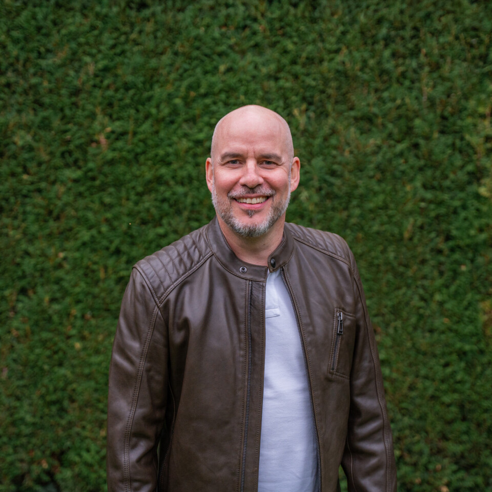 Mann vor grüner Hecke